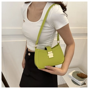 Détail du sac selle en cuir vert clair avec fermoir doré porté à l'épaule sur modèle