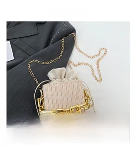 Detail of cream drawstring bucket bag with ripple texture and chunky gold chain