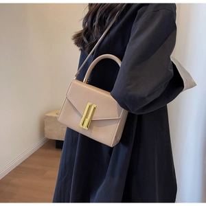 Minimalist beige small square bag with top handle and gold hardware in detail
