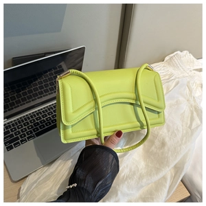 Detail of neon green crocodile texture handbag with wavy stitching and gold hardware