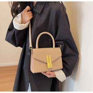 Close-up of beige lychee texture leather handbag featuring a gold vertical metal lock