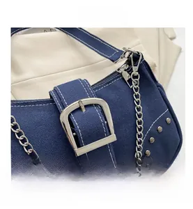 Detailed macro view of dark blue denim shoulder bag with silver buckle and chain