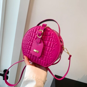 Pink round crossbody bag with crocodile pattern and golden metal hardware