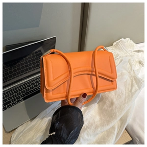 Detail of a bright orange quilted leather baguette bag with silver hardware and handle