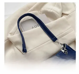 Detailed macro view of dark blue denim handbag with silver buckle and metallic chain strap