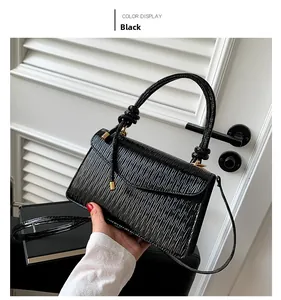 Close-up of black crossbody bag featuring vertical pleats and golden metal hardware