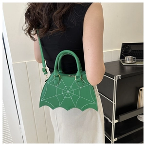 Detail of green bat wing crossbody bag with spider web stitching worn by a model