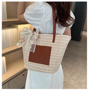Detail of woven straw tote bag with brown leather straps and pink floral lace bow