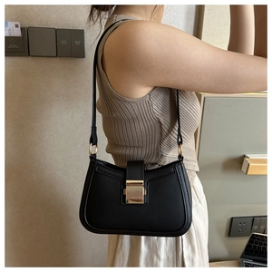 Détail d'un sac sous le bras noir avec une boucle carrée dorée et une texture en cuir mat