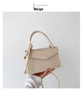 Detail of beige shoulder bag with vertical pleats and decorative knot on the handle