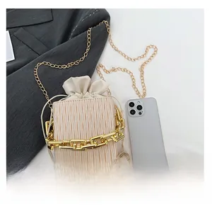 Mini cream bucket bag with chain strap compared with a phone for size demonstration