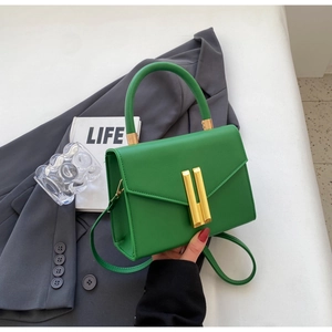 Close-up of vibrant green litchi texture leather bag with elegant golden H-buckle