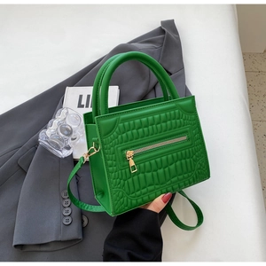 Detail of green crocodile pattern shoulder bag with gold zipper and stylish handle