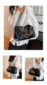 Détail du sac cabas en cuir noir brillant montrant le décor argenté et la chaîne