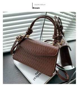 Detail of dark brown crossbody bag with horizontal ripples and knotted handles