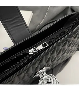 Detail of smooth silver zipper and quilted leather texture on a black shoulder bag