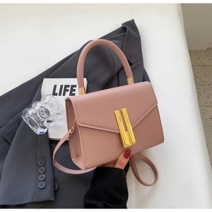 Close-up of pink leather handbag with gold metal lock and detachable shoulder strap