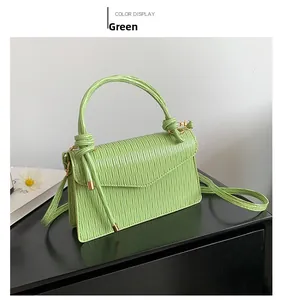 Detail of mint green bag with pleated leather texture and gold hardware accents