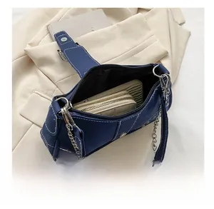 Detail of dark blue denim hobo bag with white stitching and metal rivets showing large capacity