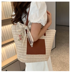 Détail du sac cabas en paille avec anses marron et nœud en dentelle brodé de fleurs