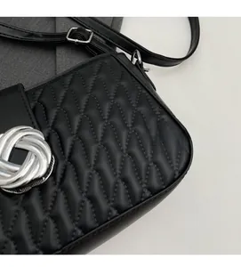 Detail of black quilted shoulder bag featuring silver interlaced metal buckle and soft fabric
