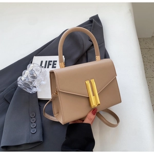 Detail of khaki leather crossbody bag with golden metal lock and round top handle