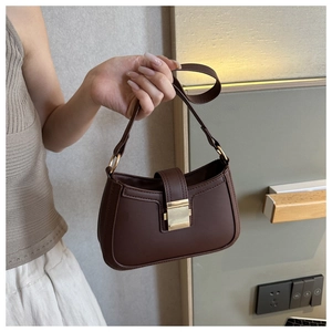 Détail du sac baguette en cuir marron foncé avec fermoir métallique doré et anse élégante