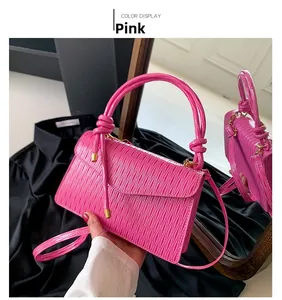 Detail of a bright pink ruched handbag with a knotted handle and magnetic flap closure