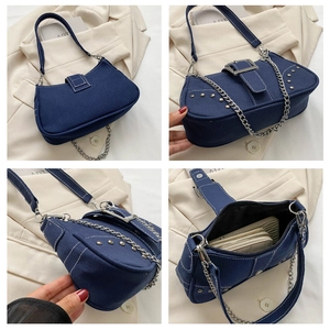 Detail view of denim underarm bag with silver rivets, chain strap and spacious interior