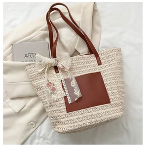Gros plan du sac cabas en paille avec poche en cuir marron et ruban en dentelle fleurie