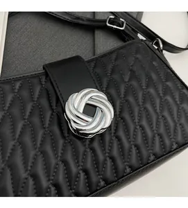 Close-up of black quilted leather shoulder bag featuring a silver woven metal buckle