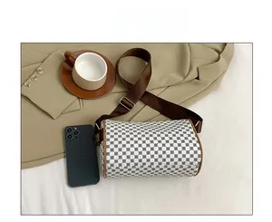 Detail of a vintage-patterned cylinder bag with brown leather trim and wide strap