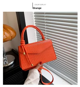 Detail of orange handbag showing elegant water ripple texture and knotted handle decor