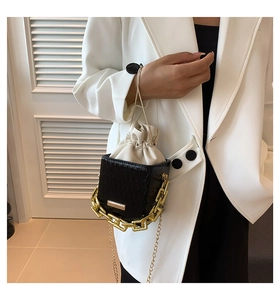 Close-up of black leather box bag with gold chain and cream drawstring liner details