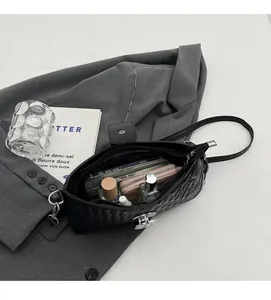 Detailed view of the black quilted shoulder bag interior holding phone and perfume