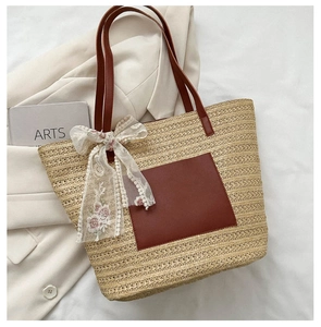 Détail du sac cabas en paille avec poche en cuir et nœud en dentelle florale élégant