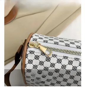 Detail of smooth golden metal zipper and black clover pattern on white cylinder bag