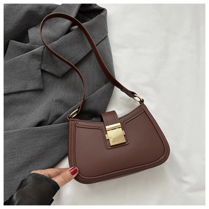 Détail d'un sac sous les bras marron foncé avec une boucle carrée en métal doré brossé