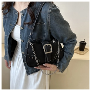 Close-up of black canvas shoulder bag with silver buckles and Y2K aesthetic metal chain