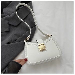 Détail du sac bandoulière en cuir blanc avec boucle dorée posé sur une veste grise
