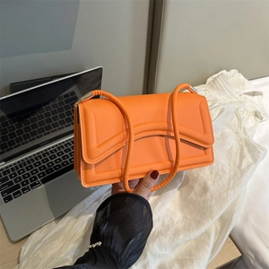 Quilted bright orange rectangular shoulder bag with puffy leather texture and silver hardware