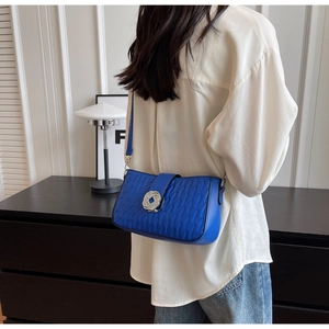 Macro view of electric blue quilted baguette bag with silver metallic knot clasp