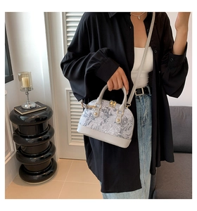 Detailed side view of shell crossbody bag with floral print and gold-tone hardware