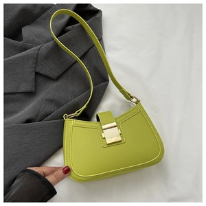 Détail du sac baguette vert avocat avec fermoir doré sur fond de tissu texturé
