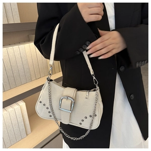 Detail of a beige canvas underarm bag with silver square buckle, rivets and metal chain