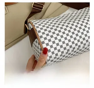 Detail of a cylinder bag featuring black clover print and brown synthetic leather trim