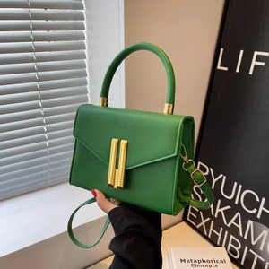 Bright green lychee grain leather crossbody bag with a gold metal lock and top handle