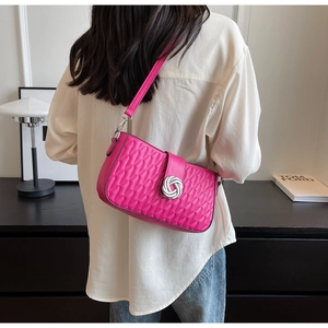 Hot pink quilted shoulder bag with silver ring buckle shown on a model in white shirt