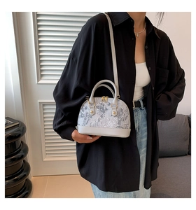 Elegant woman carrying a grey shell bag with floral patterns in a modern setting