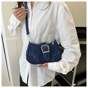 Detailed close-up of dark blue denim shoulder bag with white stitching and metal buckle